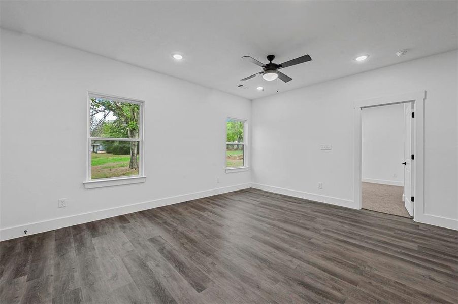 Unfurnished room featuring a healthy amount of sunlight, ceiling fan, and dark hardwood / wood-style flooring