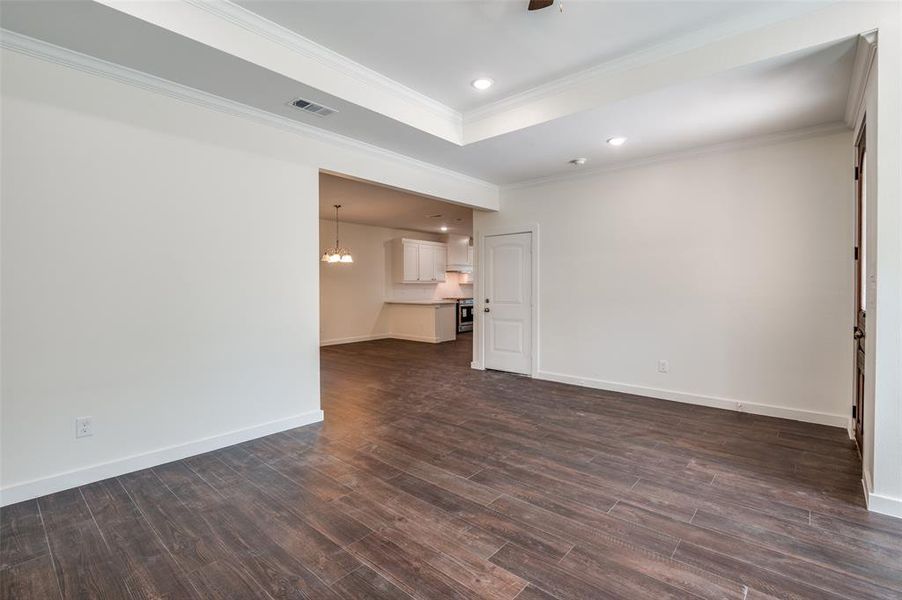 Unfurnished living room featuring crown molding and dark hardwood / wood-style flooring