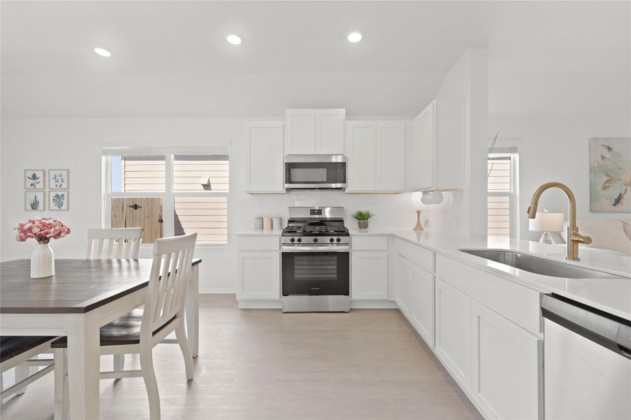 This contemporary kitchen combines high-end functionality with style, featuring a full suite of stainless steel appliances, a five-burner gas range, and a spacious dining area flooded with natural light.
