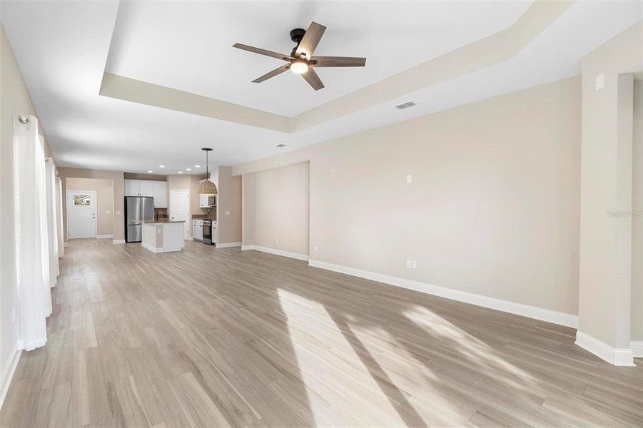 The great room, with its elegant tray ceiling, seamlessly flows into the dining area and kitchen, creating a spacious yet connected layout. Designed for both convenience and comfort, this space allows you to stay engaged in every moment while also providing the perfect setting to unwind and relax.