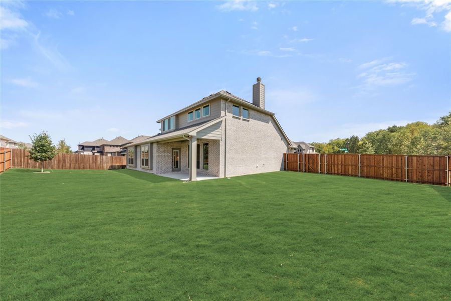Two-story brick home with covered patio, large fenced backyard, and green lawn Two-story brick home with covered patio, large fenced backyard, and green lawn