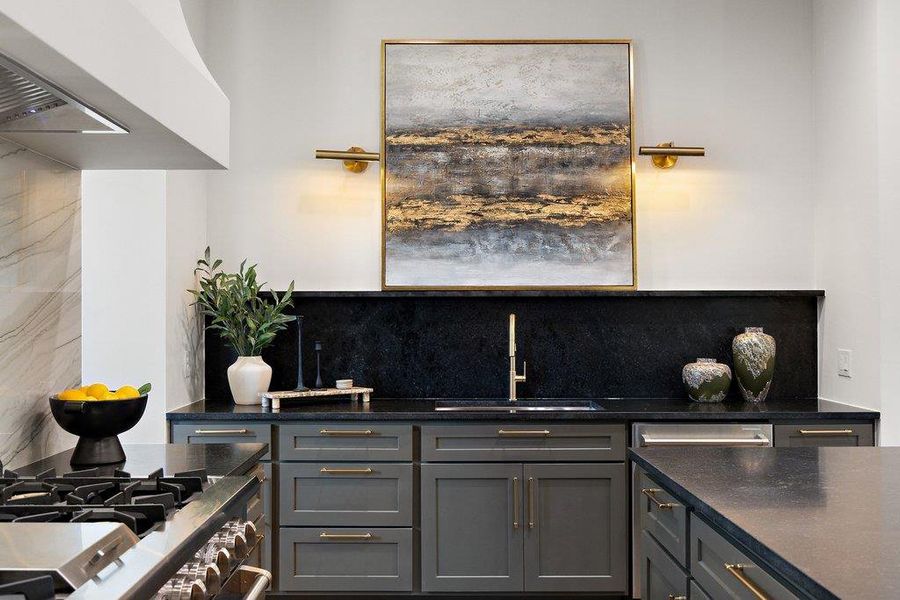 A refined kitchen design featuring dark cabinetry and a striking gold faucet.