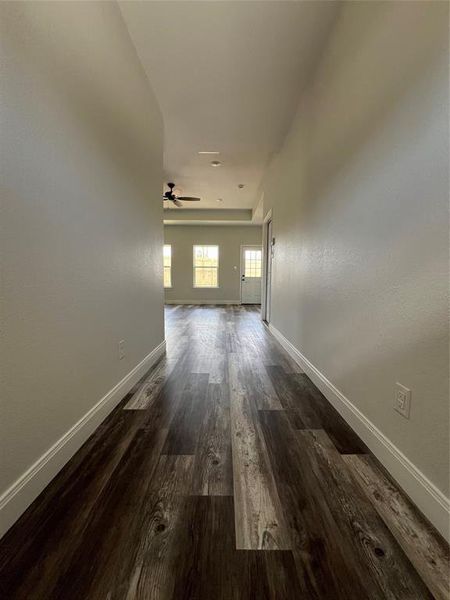 Hallway featuring dark wood finished floors and baseboards