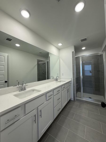 Bathroom with double vanity, a stall shower, dark tile patterned floors, and recessed lighting