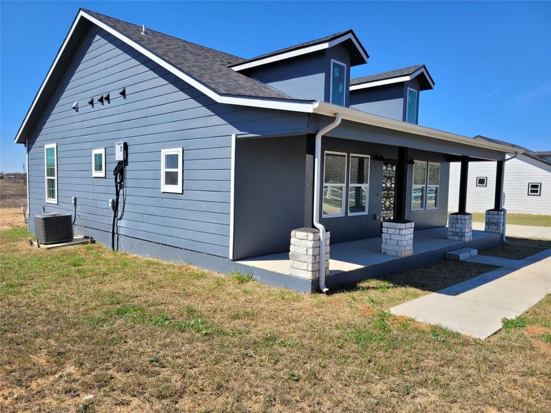 Rear view of house featuring a porch and a yard