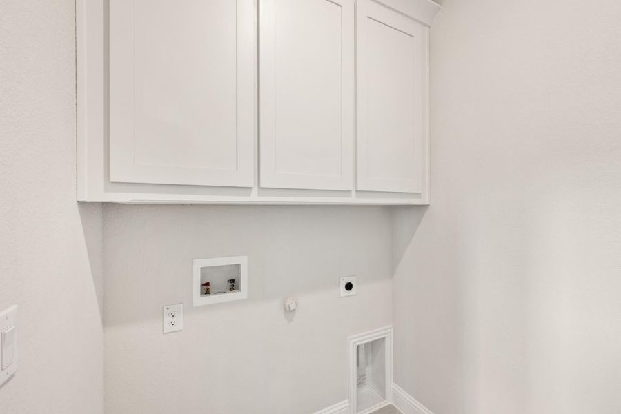 Laundry room with white upper cabinets, washer and dryer hookups, and dryer vent outlet