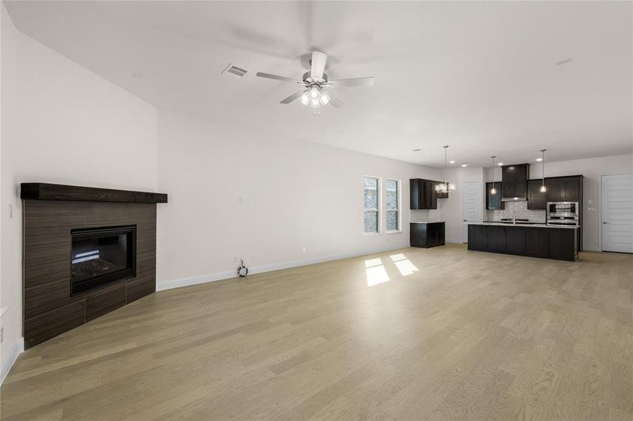 Unfurnished living room featuring a fireplace, light wood-type flooring, a ceiling fan, and recessed lighting