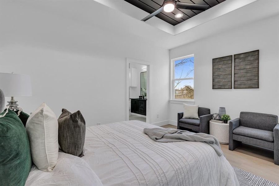 Bedroom with a tray ceiling, ensuite bath, ceiling fan, and light hardwood / wood-style floors