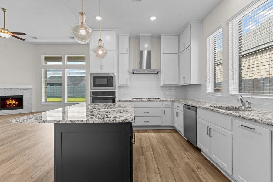Kitchen design highlights a spacious layout with white cabinetry, walk-in pantry, and seamless connection to the family room. Look at the deep undermount stainless steel sink and all the granite counters that will surround you!  Notice how the gourmet kitchen flows gracefully into the amazing large family area!