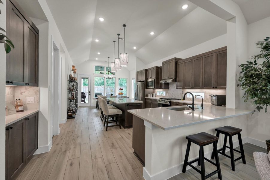 Beautiful chef-inspired kitchen featuring an oversized island, upgraded Cashmere Taj quartz countertops, designer pendant lighting, and abundant cabinetry with soft-close drawers.