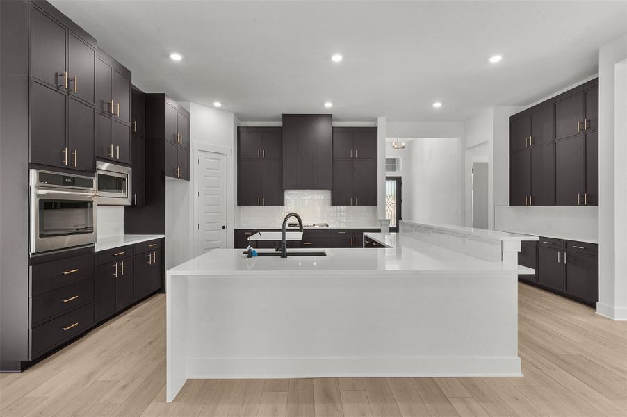 Kitchen featuring light stone counters, recessed lighting, decorative backsplash, stainless steel appliances, and light wood-style floors
