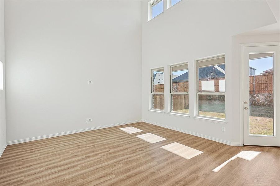 Empty room featuring light wood-type flooring and a high ceiling