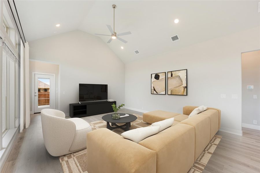 Living room with vaulted ceiling, ceiling fan, tan sectional sofa, and wall-mounted TV on light hardwood floors