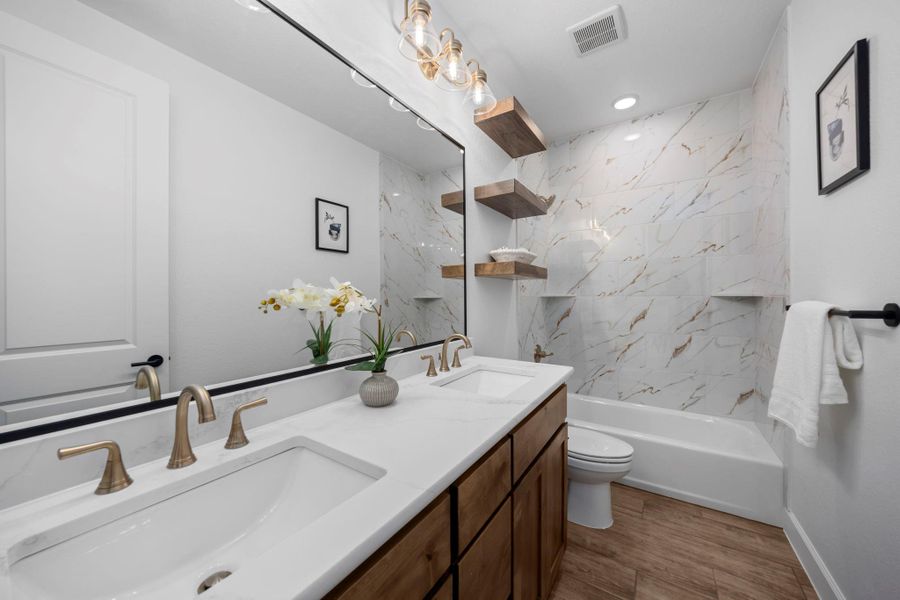 Bathroom with double vanity, shower / washtub combination, and light wood-style flooring