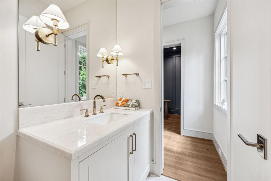 Behind the kitchen, tucked discreetly out of sight, is the powder room. With plenty of space, marble counters, and polished gold fixtures, you and your guests will feel comfortable and taken care of. Behind the kitchen, tucked discreetly out of sight, is the powder room. With plenty of space, marble counters, and polished gold fixtures, you and your guests will feel comfortable and taken care of.