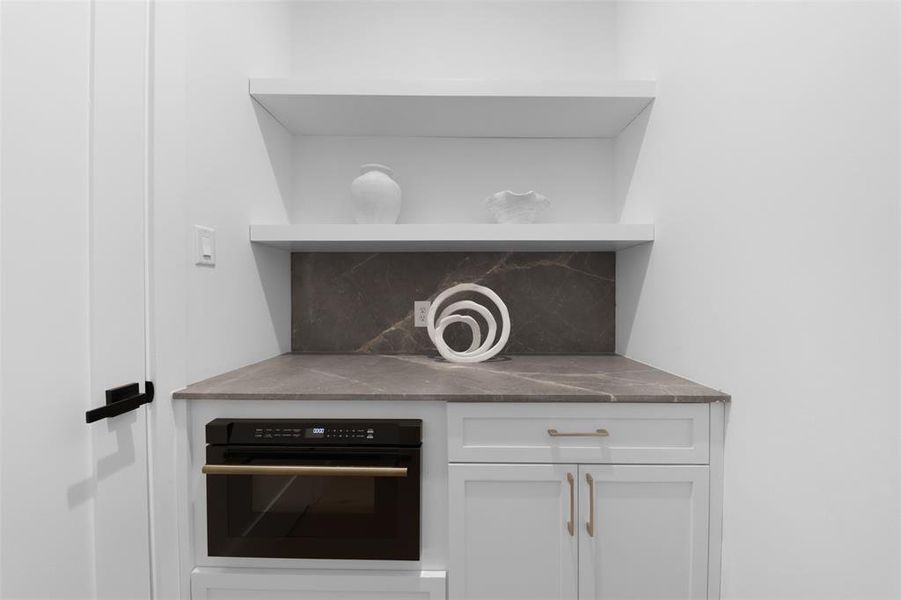 Detailed view of open shelves, white cabinets, oven, and tasteful backsplash