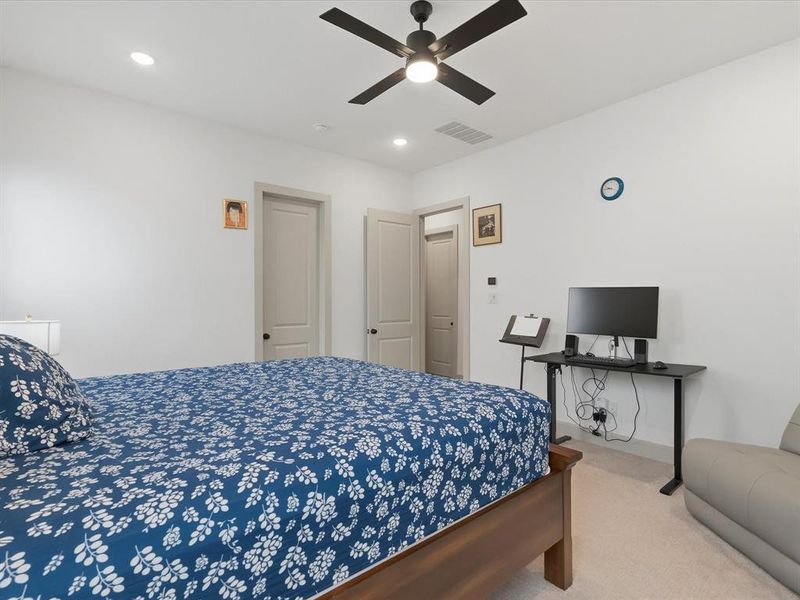 Recessed lighting illuminates this room featuring light-toned carpeting and a ceiling fan