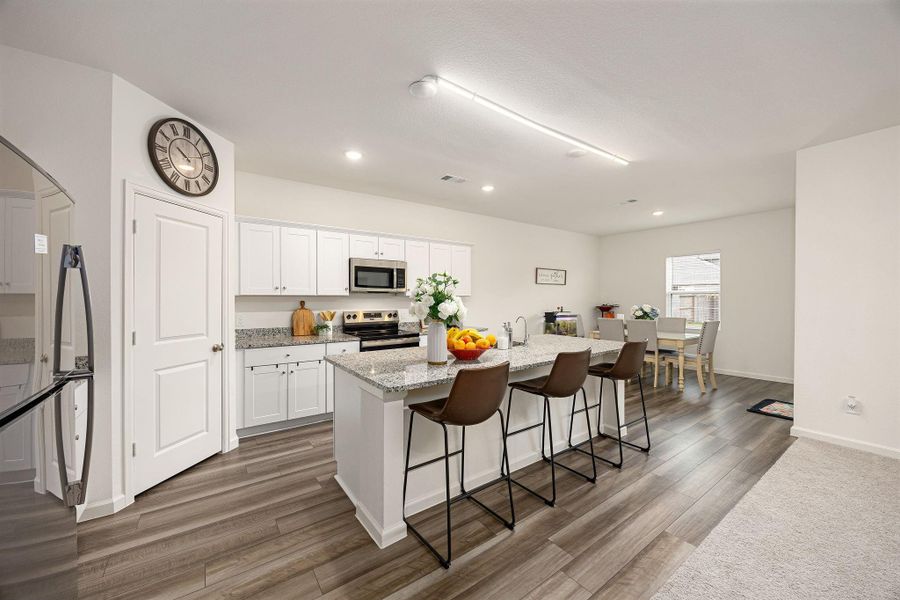 Kitchen with granite countertops, large island with sink, and breakfast bar.