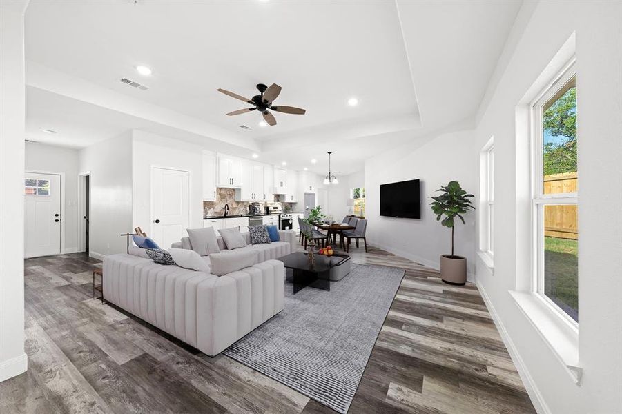 Living area featuring a chandelier, dark wood-type flooring, a tray ceiling, recessed lighting, and a ceiling fan Living area featuring a chandelier, dark wood-type flooring, a tray ceiling, recessed lighting, and a ceiling fan