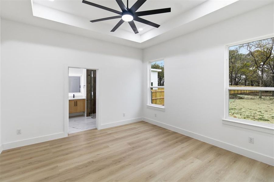 Empty room featuring light wood-style floors, a tray ceiling, ceiling fan, and recessed lighting