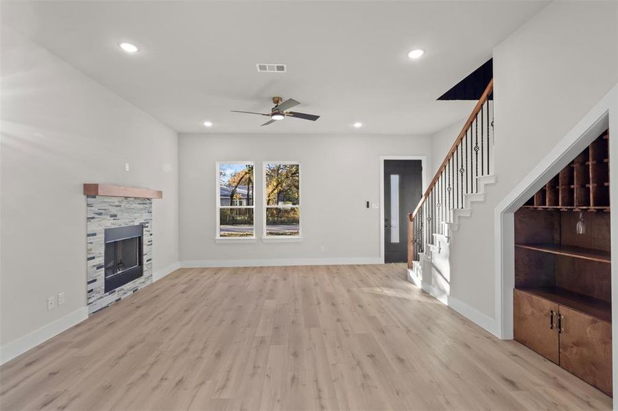 Unfurnished living room featuring light hardwood / wood-style flooring, ceiling fan, and a tiled fireplace