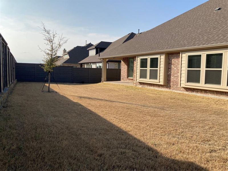 Over-sized, grassy, and private backyard with a covered patio and wood fence Over-sized, grassy, and private backyard with a covered patio and wood fence