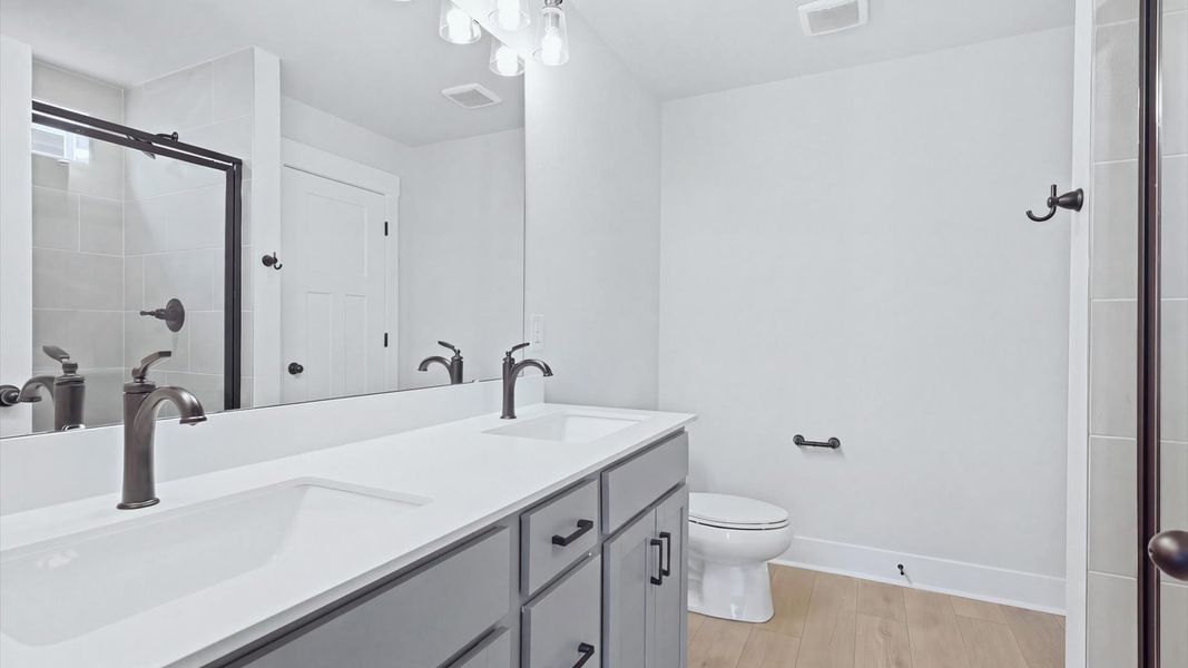 Memorable mornings begin in this elegant primary bathroom with walk-in shower and double vanity by DRB Homes
