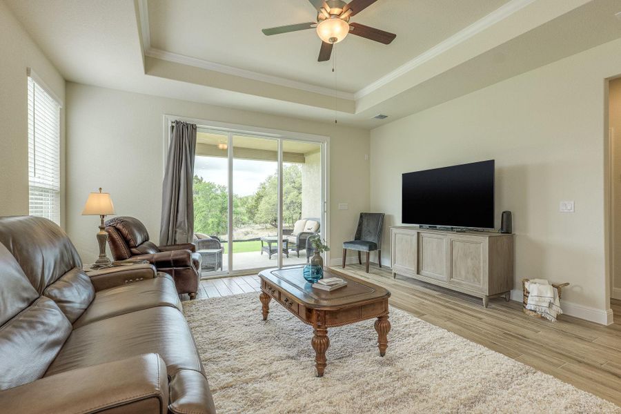Living area featuring a ceiling fan, crown molding, healthy amount of natural light,  and a tray ceiling