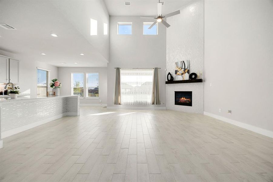 Another view of the living room, seamlessly flowing into the kitchen, showcasing the cozy fireplace, with a clear view to the backyard.