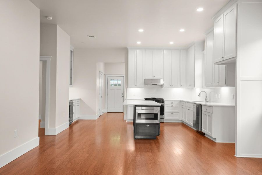 A well-lit, open-concept kitchen features bright cabinetry and gleaming hardwood flooring. A well-lit, open-concept kitchen features bright cabinetry and gleaming hardwood flooring.