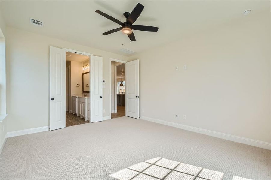 Unfurnished bedroom with ceiling fan, light carpet, and ensuite bathroom