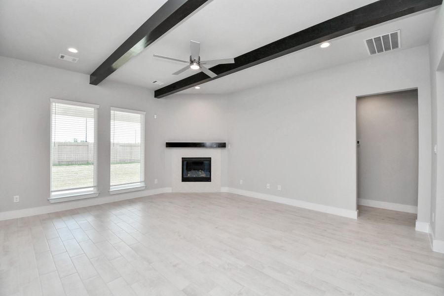 Family room flooded with natural light through the expansive windows.  The premium tile flooring adds a touch of luxury to the space, creating the perfect setting for relaxing moments and cherished gatherings with loved ones. Sample photo of completed home with similar floor plan. Actual colors and selections may vary.