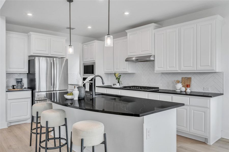 A well-lit kitchen with sleek black countertops and an inviting island for casual dining.