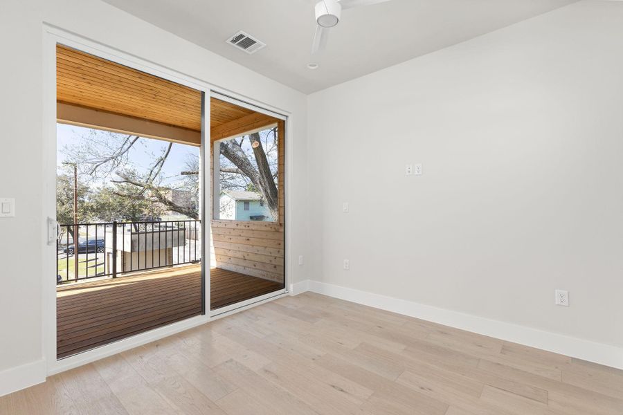 Empty room featuring visible vents, light wood-style flooring, a ceiling fan, and baseboards