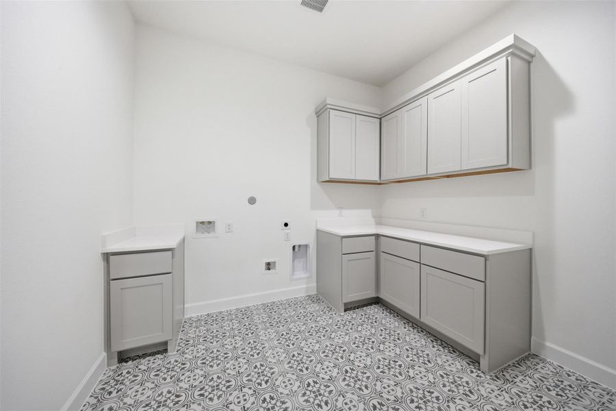 Bright and functional utility room featuring custom cabinetry, generous counter space