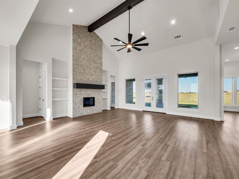 Unfurnished living room featuring a fireplace, hardwood / wood-style floors, beamed ceiling, high vaulted ceiling, and built in shelves