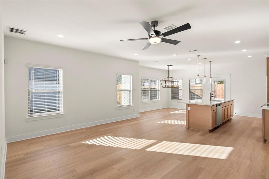 Unfurnished living room featuring light wood-type flooring, recessed lighting, ceiling fan, and a chandelier