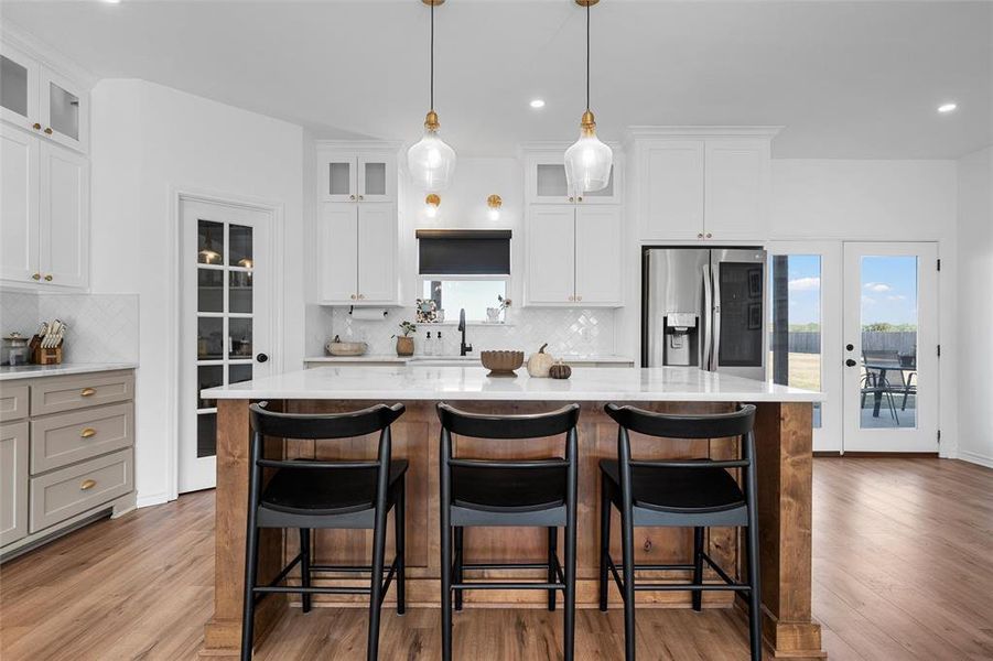 Kitchen featuring a kitchen island, recessed lighting, stainless steel fridge, decorative backsplash, and light stone counters