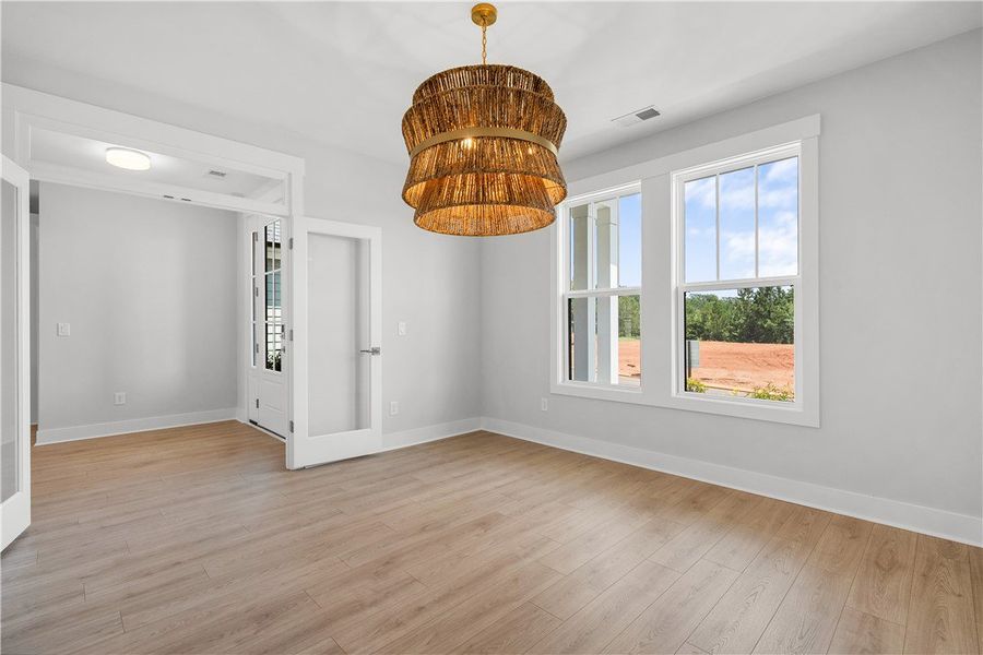 A spacious room features a unique chandelier, tall A spacious room features a unique chandelier, tall