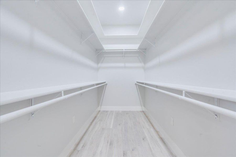 Spacious closet featuring wood finished floors with plenty of shelving for storage Spacious closet featuring wood finished floors with plenty of shelving for storage