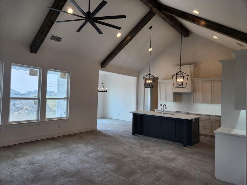 Kitchen featuring a center island with sink, high vaulted ceiling, beam ceiling, sink, and decorative light fixtures