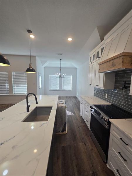 Kitchen with electric range oven, white cabinets, light stone countertops, decorative light fixtures, and recessed lighting