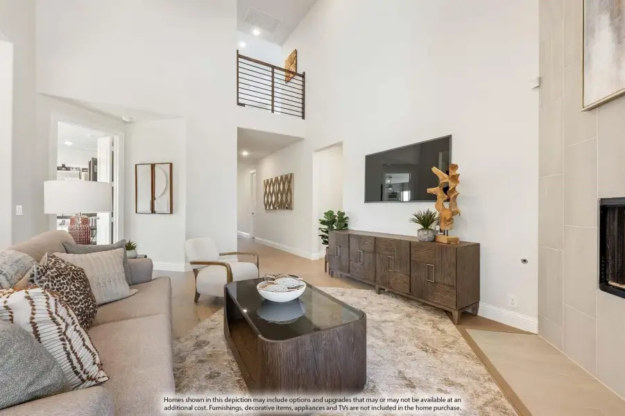 Living room with two-story ceiling, wood floors, fireplace, and open second-floor balcony overlook
