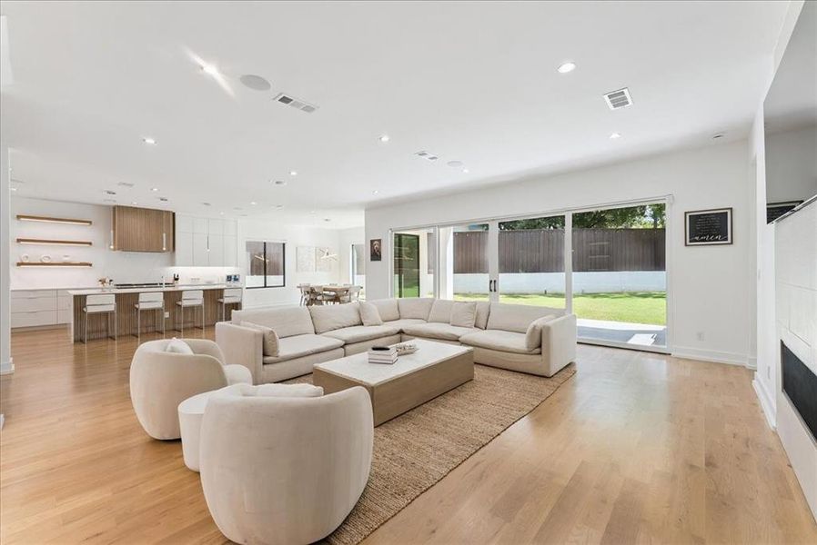 Living room featuring light wood-type flooring, recessed lighting, and a fireplace