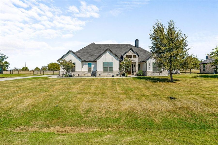 View of front of house with board and batten siding, a chimney, and stone siding