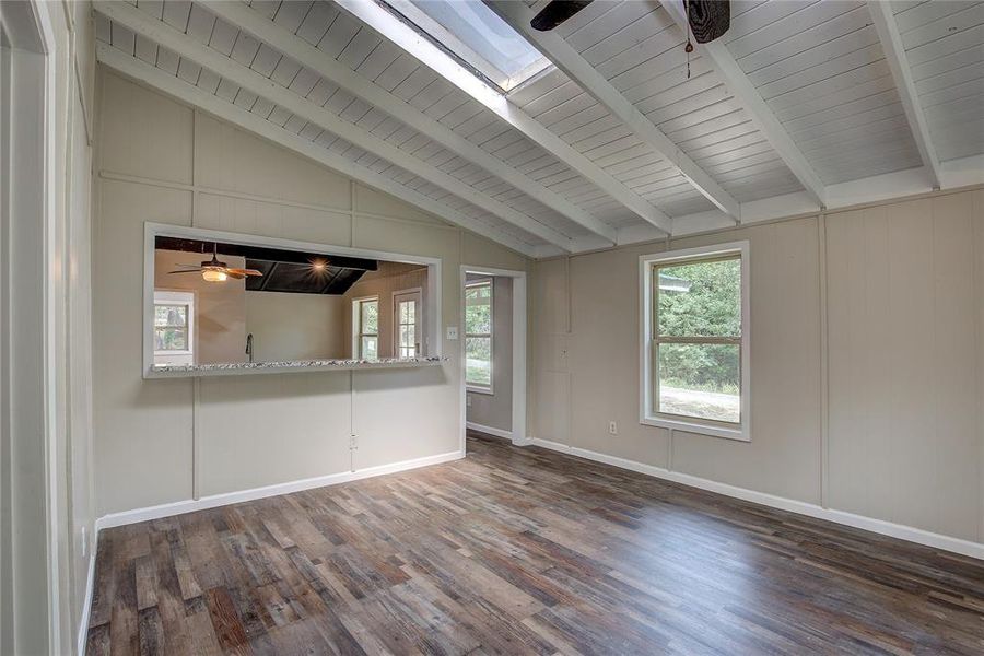 Unfurnished room featuring ceiling fan, wooden ceiling, dark hardwood / wood-style floors, and vaulted ceiling with skylight