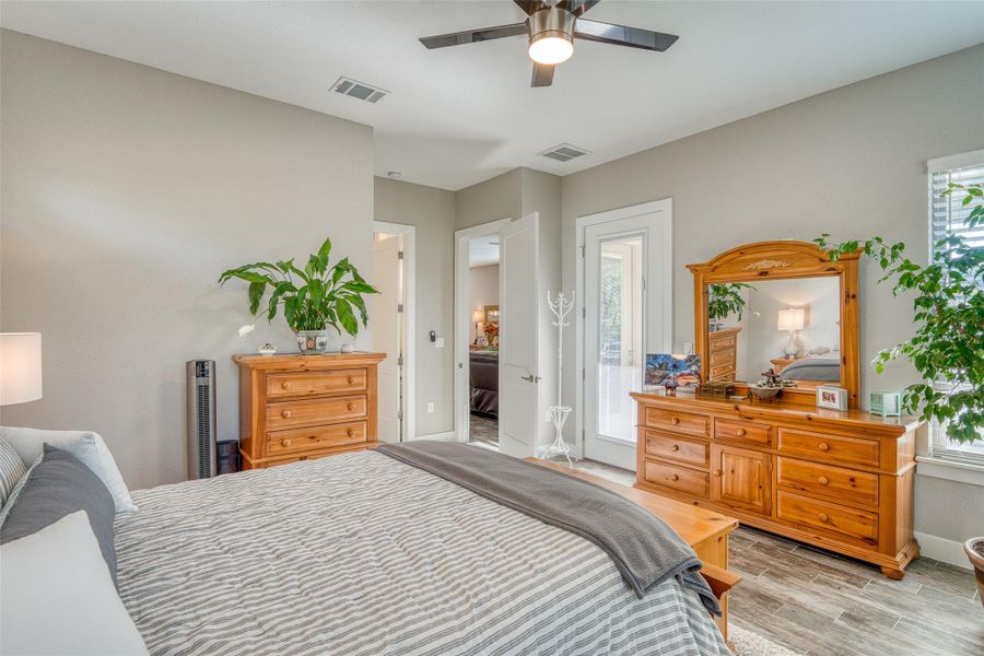 Bedroom featuring multiple windows, light wood-style floors, a ceiling fan, and access to exterior
