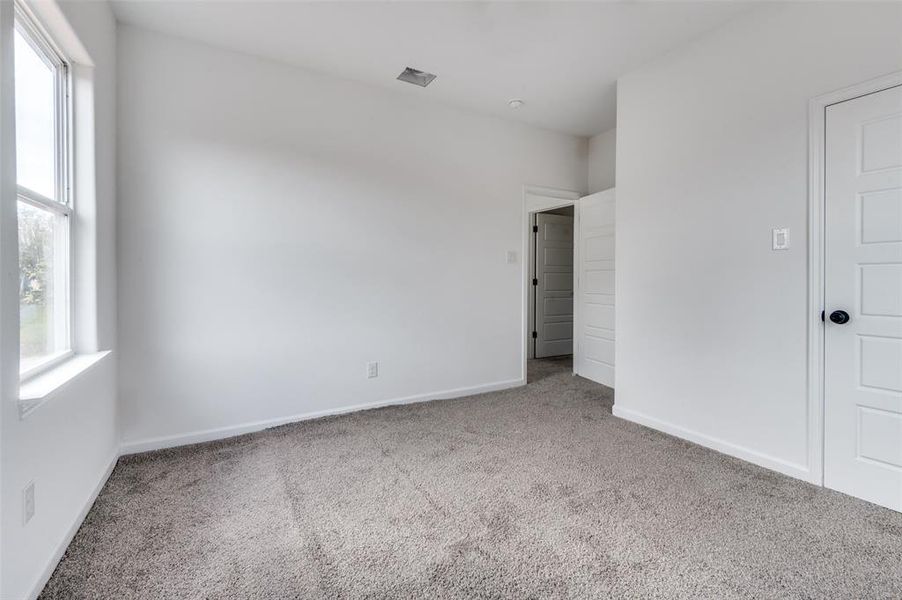 Empty room with carpet floors and a healthy amount of sunlight