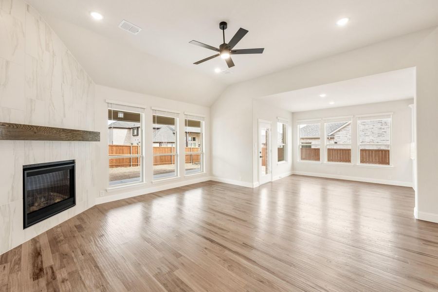 Open living room with hardwood floors, tile fireplace, vaulted ceiling, and ceiling fan