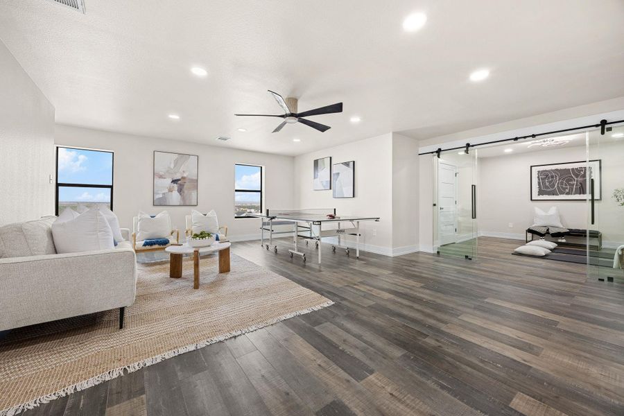 Living area with a barn door, recessed lighting, dark wood-style flooring, and ceiling fan Living area with a barn door, recessed lighting, dark wood-style flooring, and ceiling fan